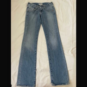 Ljusblå bootcut jeans från Lee - Snygga ljusblå jeans från Lee med klassisk bootcut-modell. Jeansen har två fickor, bälteshällor och Lee-logga på bakfickan. Tillverkade i mjukt denim med lätt slitning för en avslappnad vibe. 