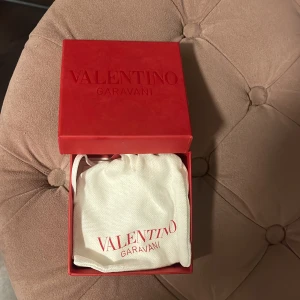 Valentino Garavani svart armband - Snyggt svart armband från Valentino Garavani med ikoniska pyramidformade nitar i guld☺️, Armbandet är gjort i skinn och har ett coolt, edgy uttryck med guldfärgade detaljer och spänne. Kommer med original ask och dustbag.Använt fåtal gånger, säljer då jag inte använder den💓