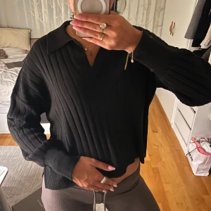 Svart ribbad tröja från ONLY - Svart ribbad tröja från ONLY med krage och v-ringning. Tröjan har lång ärm och en loose passform, perfekt till jeans eller kjol. Materialet är stickat och känns mjukt mot huden. Enkel men ändå snygg att styla till olika looks. Aldrig använd så som ny!❤️