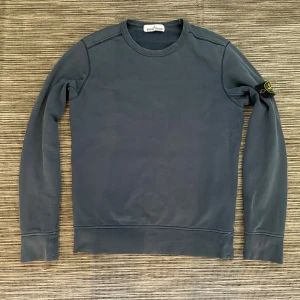 Stone Island tröja - Säljer en snygg blå långtröja från Stone Island! Tröjan är i mycket bra skick förutom några små små hål vid handlederna. Skriv om ni vill ha bättre bilder på hålen. Annars mycket bra! Scannar man qr-koden eller skriver koden i certilogo så får man upp att den är autentisk. Får även med en extra knapp vid alla tvättlappar. Skicka till mig om ni vill ha fler bilder. Om ni har några andra frågor så är det bara att höra av er!😊 