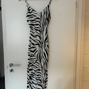 Zebramönstrad långklänning med smala axelband - Köpt på Bershka i storleken XS. Snygg långklänning med zebramönster i svart och vitt. Klänningen har smala axelband och en figurnära passform. 