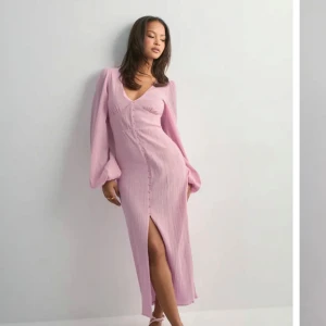 Ljusrosa långklänning med slits - Säljer en ljusrosa långklänning med v-ringning och långa puffärmar. Klänningen har knappar framtill och en snygg slits💗