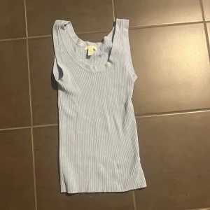 Ljusblå ribbad linnetopp H&M XS - Supersöt ljusblå ribbad linnetopp från H&M i storlek XS. Toppen är ärmlös med breda axelband och har en klassisk rund halsringning. Perfekt till jeans eller shorts för en chill look. Mjuk och stretchig bomullskänsla.
