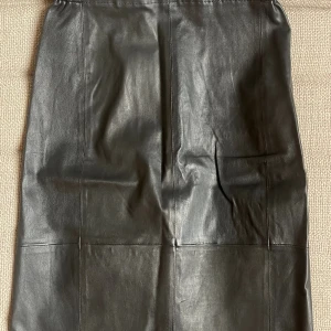 Svart skinnkjol från InWear - Snygg svart långkjol i äkta skinn från InWear. Kjolen har en rak passform med elastisk midja och stilrena sömdetaljer. Modellen heter Luella Skirt Premium.