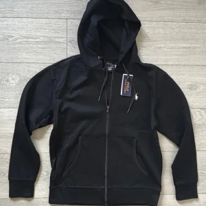 Polo Ralph Lauren zip-hoodie - Helt ny Ralph Lauren zip-hoodie med dragkedja och huva. Klassisk design med vit broderad logga på bröstet, känguruficka och snörning i huvan. Tillverkad i mjuk bomull, perfekt för en och stilren look. Kom med frågor!😁
