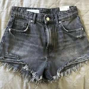 Grå högmidjade jeansshorts - Snygga grå jeansshorts från Zara med hög midja och fransiga kanter. Shortsen har slitna detaljer och klassisk femficksdesign. Helt nya och oanvända, lapparna sitter även kvar!!⭐️⭐️💓