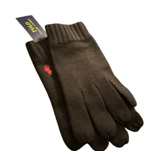 Stickade ullhandskar Polo Ralph Lauren - Svarta stickade handskar från Polo Ralph Lauren med klassisk röd logga broderad på ovansidan. Helt nya - aldrig använda, perfekta för kyliga dagar. Nypris: 1200 kr - Mitt pris: 800 kr