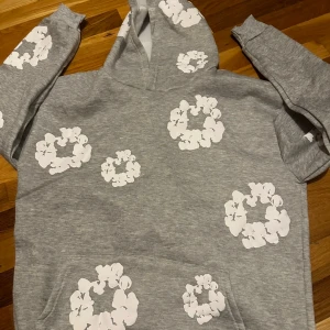 Accepterar bud‼️Grå hoodie med vita blommor - Grå hoodie med vita blommor i cirkelformade mönster över hela tröjan. Tröjan har huva och en stor magficka framtill. Perfekt för dig som gillar en chill och snygg streetstil.