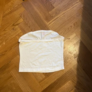 Vit sleeveless top i bomull - En enkel och stilren vit top i mjukt bomullsmaterial. Kjolen har rak passform och är helt utan mönster eller detaljer, vilket gör den lätt att matcha med olika toppar. Perfekt för dig som gillar minimalistisk stil och vill ha en basic kjol i garderoben.