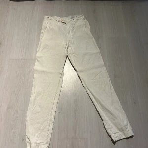 Vita linnebyxor från Kanaljen - Snygga vita linnebyxor från Kanaljen, tillverkade i 100% lin. Byxorna har en avslappnad passform. De har dragkedja och knapp framtill samt fickor på sidorna och bak. En bakficka saknar en knapp (se bild 5) Perfekta för en chill och stilren look under varmare dagar. Köpta i en butik i Skåne för 800kr. Tveka inte på att höra av er om prisförslag eller om ni vill ha bilder eller mått.