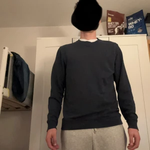 Mörkblå basic långärmad tröja - En stilren mörkblå långärmad tröja med rund halsringning. Tröjan har en enkel och clean design utan tryck eller mönster, perfekt för dig som gillar en minimalistisk look. Passformen är normal och materialet känns mjukt och bekvämt.