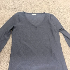 Blå långärmad topp från JDY XS - Snygg blå långärmad topp från JDY i storlek XS. Toppen har ett subtilt blommigt mönster i tyget och en v-ringad hals. 