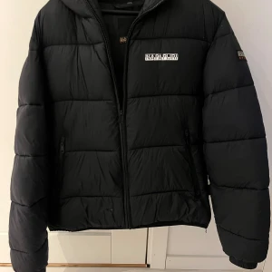 Napapirji Vinterjacka S - Napapirji vinter jacka i bra skick, dock finns ett litet hål som sys på sista bilden, men sitter en lagning på nu så syns inte längre och försämrar heller inte funktionen. Varm jacka som är endast använd en vinter och är i bra skick. Storlek S. Svart. Nypris ca 2800kr