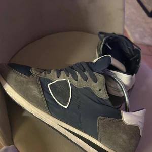 Philippe Model sneakers i blå och grå - Köpta i december acceptabelt skick säljer pga för små 41 storlek defekt ett sytt hål där framme som du ser på bild 5 och under sulan är det slitet…