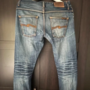 Nudie Jeans Grim Tim Dry Selvage - Tja! Säljer ett par sällsynta, helt otroligt snygga selvage nudie jeans i modellen grim tim! Jeansen har en del lagningar som bygger karaktär, mesta dels i skrevet. Det finns ett litet hål i skrevet som man kan se på bild 4 som kan fixas gratis i en nudie jeans butik! Pris kan diskuteras! Nypris: 2200💸