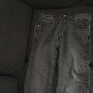 Grå jeansbyxor  - Säljer ett par grå jeansbyxor i klassisk rak modell. Byxorna har fem fickor, bälteshällor och stängs med knapp och dragkedja. Perfekt för dig som gillar en enkel och stilren look. Storlek W32 L32.