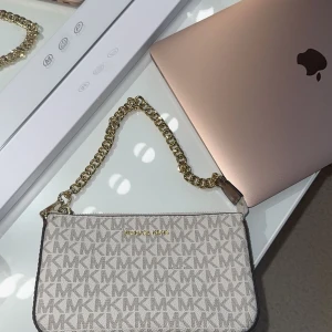 Michael Kors handväska- vanilla - Nästan helt ny Storlek One size  Köpt förra sommaren (kvitto finns)  Vanilla (vit/beige med logga) Utvändigt material: Polyvinylklorid, polyuretan, bomull, polyester Foder: Textil   Snygg och stilren väska från Michael Kors i den populära “vanilla”-färgen. Perfekt storlek för mobilen, kort och andra småsaker – både praktisk och trendig! Passar lika bra till vardags som till fest.🩷