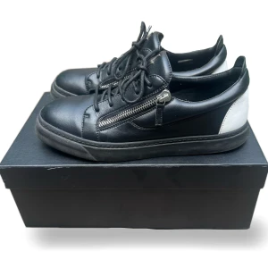 Vit/Svart Giuseppe Zanotti Sneakers - Jag säljer dessa otroligt fräscha Giuseppe Zanotti Frankie sneakers. Inga skador på skorna. Skorna är självklart äkta och sparsamt använda, mycket fint skick. Nypris ligger på drygt 6000kr. Dessa fungerar fint både till fest och vardag. Storlek 43. Box och dustbag medföljer.