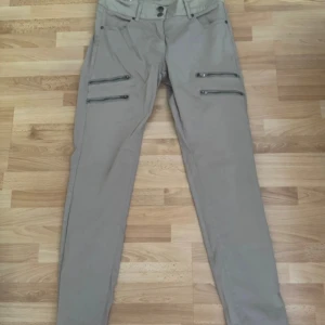 Beiga cargopants från House of Soul - Snygga beiga cargopants från House of Soul med fyra dragkedjefickor framtill och dubbla knappar i midjan. Byxorna har raka ben och är tillverkade i ett mjukt bomullsmaterial. Perfekta för en chill och trendig look. Använd en gång.