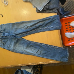 Blå raka jeans från Levi's 501 - Klassiska blå jeans från Levi's 501 med rak passform och femficksdesign. Jeansen har normal midja och är tillverkade i slitstarkt denimtyg. Perfekta för en avslappnad och tidlös stil.