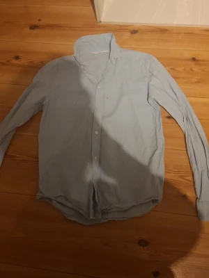HM Skjorta  - En enkel och stilren ljusblå skjorta med klassisk krage och knäppning framtill. Skjortan har långa ärmar och är tillverkad i ett mjukt material som känns skönt mot huden. Perfekt för en avslappnad men ändå snygg look. Kan såklart gå ner i pris! 