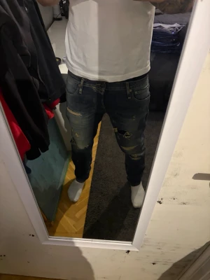 Blå slitna skinny jeans med patchar jack and jones - Säljer ett par blå skinny jeans med slitningar och patchar på både fram- och baksida. Jeansen har låg midja och klassisk femficksdesign. Perfekta för dig som gillar en edgy och trendig stil. jack and jones w31 l32 hål i knä