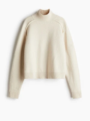 Krämvit stickad tröja med polokrage - En stilren krämvit stickad tröja med hög polokrage och ribbade muddar vid ärmslut och nederkant. Tröjan har en rak passform och långa ärmar, perfekt för lager på lager. Materialet ser mjukt och varmt ut, idealiskt för kyligare dagar. Nypris 300. Skriv för fler bilder!