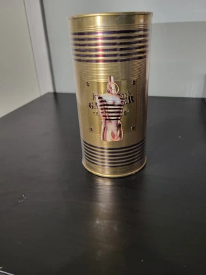 Jean Paul Gaultier Le Male 125ml - Säljer en Jean Paul Gaultier Le Male parfym i metallburk på 125 ml. Burken är guldig med svarta ränder och har en ikonisk design med en manlig torso i randig tröja på framsidan. Perfekt för dig som gillar klassiska och stilrena dofter.