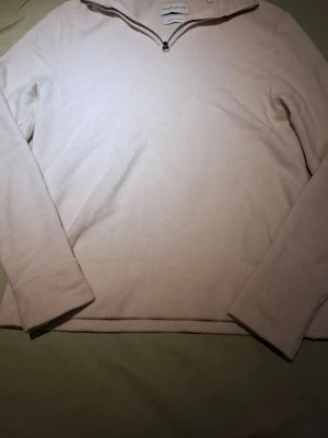 Beige merinoulltröja från These Glory Days - Snygg beige stickad tröja från These Glory Days i mjuk superior merinoull. Tröjan har halv dragkedja vid halsen och långa ärmar. Perfekt för lager på lager och enkel att matcha med olika outfits.