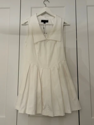 Vit klänning med krage - Supersöt vit klänning från Zara med krage och ärmlös design. Kjolen är veckad och klänningen har en lätt A-linjeform. Ej använd men provades en gång därav en sminkfläck.