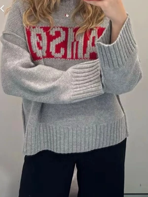 Grå stickad tröja med röd text - Oversized grå stickad tröja med breda ribbade muddar och röd textdetalj över bröstet, använd få gånger ( Nypris - 2195kr )!!!❤️❤️