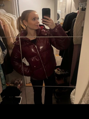 Glansig vinröd pufferjacka - Glansig röd pufferjacja från Nelly. Använd Max 5 gånger så superfint skick🥰