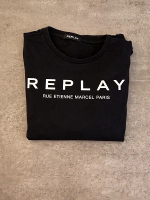 Replay T-shirt  - Stilren Svart t-shirt från Replay | Tröjan är använd ett flertal gånger | Inge defekter förutom slitningar på det vita trycket | Skriv till mig för fler bilder | Hör av dig vid funderingar📩