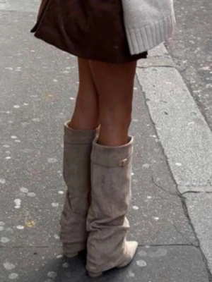 Beiga mockastövlar med spetsig tå - Snygga beiga stövlar i mocka med slouchy passform och spetsig tå. Stövlarna har en hög skaftlängd och en liten dekorativ detalj upptill. Perfekta att styla med kjol eller klänning för en trendig look. HELT OANVÄNDA OCH NYA!! 