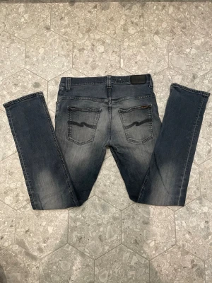 Nudie jeans  - Bra skick överlag. Innerfickan på höger sida är ihopsydd (var tidigare sprucken). Lagningen sitter nu och påverkar inte användningen, men kan inte garantera hur länge den håller. Syns inte när jeansen används. Jeansen har en slim passform.  Pris satt med hänsyn till detta. Hör av dig vid frågor / MVH, Milo