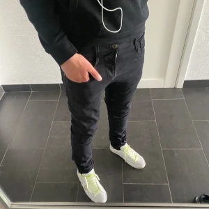 Replay Anbass jeans - Säljer ett par svarta Replay Anbass jeans i storlek 31. Är 185 Modellen har smal passform med klassiska fem fickor, dragkedja och knapp. Snyggt tapered snitt och stretchigt material som sitter skönt. Perfekta svarta jeans för dig som gillar stilrena och moderna byxor.
