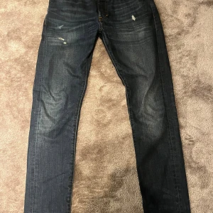 Mörkblå slim straight jeans 30 - Mörkblå jeans med slim straight passform och klassisk femficksdesign. Jeansen har lätt slitna detaljer framtill och är tillverkade i denim med snygga kontrastsömmar. Perfekta för dig som gillar en smal men rak siluett.
