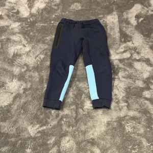 Nike blå mjukisbyxor med ljusblå detaljer - Snygga mjukisbyxor från Nike i mörkblått har lite fläckar men går bort i tvätten väldigt sköna byxor