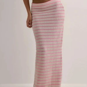 Randig långkjol i rosa och vit Nelly - Supersnygg långkjol med smala rosa och vita ränder. Kjolen är figurnära och har en ribbad, stickad känsla som sitter tajt över höfterna. 
