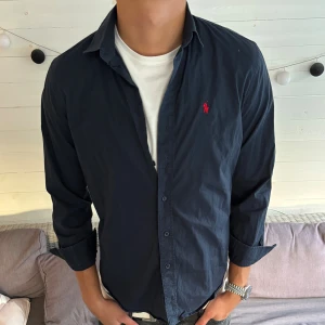 Mörkblå skjorta från Ralph Lauren - BILIGARE PÅGRUND AV ATT DE TVÅ ÖVERSTA KNAPPARNA SAKNAS Det är storlek L men den har krymt så är ca S/M