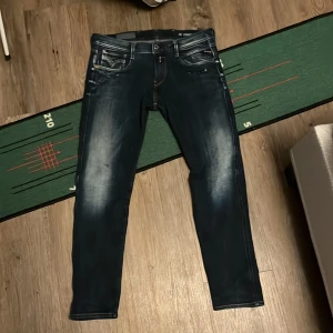 Replay mörkblå jeansbyxor med slitningar - Säljer ett par mörkblå jeansbyxor från Replay med snygga slitningar och tvättade detaljer. Byxorna har fem fickor, dragkedja och knapp i midjan samt smal passform. Perfekta för dig som gillar en modern och stilren look. W 29 L30 