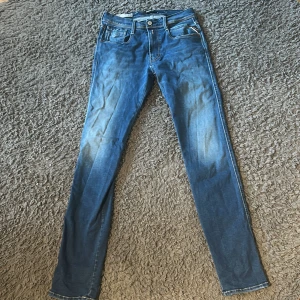 Replay Anbass Hyperflex jeans blå - Snygga blå Replay Anbass Hyperflex jeans i slim fit. Klassisk femficksmodell med guldfärgade sömmar och diskret Replay-logga vid fickan. Jeansen har en smal passform och är tillverkade i stretchigt denim för extra komfort.Priset står inte skrivet i sten!!