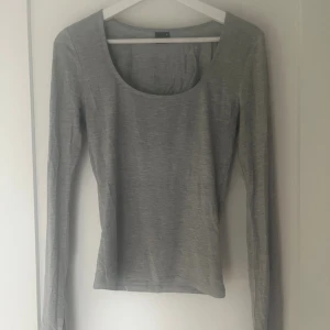 Grå topp från Gina Tricot - Grå tröja från Ginas soft touch kollektion. Har en ”slits” längst ner i ärmarna som blir en fin detalj. Har knappt använts och har inga tecken på slitage!