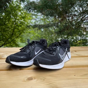 Svarta Nike löparskor  - Säljer ett par näst intill nya svarta Nike löparskor. Skorna har snörning och är tillverkade i lätt syntetmaterial med mesh för bra andningsförmåga. Perfekta för löpning eller träning. Snygg och sportig design. Det står att de är storlek 41, men Nike har lite mindre storlekar, så kolla gärna upp storleksguiden på Nikes hemsida om du känner dig osäker! Fråga mig gärna om andra funderingar om du har några:)