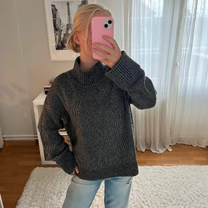 Mörkgrå stickad polotröja - Mysig mörkgrå stickad polotröja med breda ribbade detaljer och hög krage. Tröjan har en loose passform och långa ärmar, perfekt för kyliga dagar💞💞💞