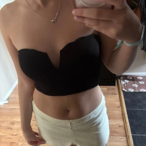 Festtop! -  svart axelbandslös tubtopp med snygg v-formad urringning framtill. Passar xs-S 