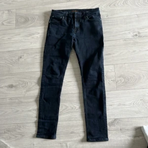 Mörkblå jeans från Nudie Jeans, W32 L32 - Snygga mörkblå jeans från Nudie Jeans i klassisk femficksmodell. Jeansen har en smal passform och raka ben, tillverkade i mjukt denimtyg. Perfekta för dig som gillar stilrena och tidlösa jeans med modern känsla.