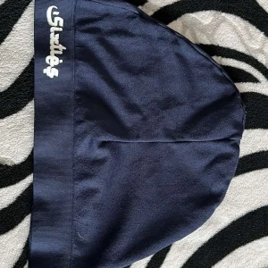 Mörkblå mössa från Sketchers - Säljer en snygg mörkblå mössa från sixties.Den är perfekt för kyliga dagar och har en enkel men stilren design. Mössan är gjord i ett mjukt material som känns skönt mot huden. Perfekt för både vardag och träning!