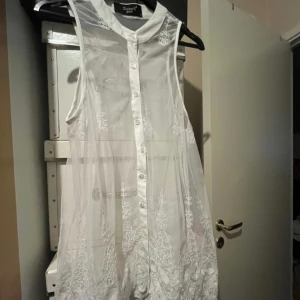 Vit ärmlös klänning från Nly One - Säljer en superfin vit ärmlös klänning från Sisters Point (Salt). Den har knappar framtill och är dekorerad med vacker spetsdetalj. Perfekt för sommarens alla fester eller en romantisk midsommarkväll. Klänningen är i nyskick.