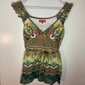 Knytbar justerbar grön blus med tryck och broderade detaljer - Super snygg blus jag hitta! Grönt abstrackt tryck med blom liknande brodering framtill. Går att justera och knyta med snörs i midjan för att få korsätform och ändra storlek. Så passar flera storlekar en S som står.